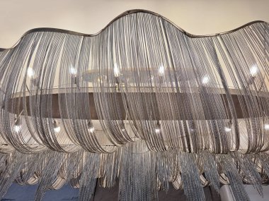 Kıvrımlı ve dalgalı yapısal tasarımı olan gümüş zincirli metal püsküllü avizeyi kapat. Bu tür avize ve zincir dokusu eşsiz ve zariftir..