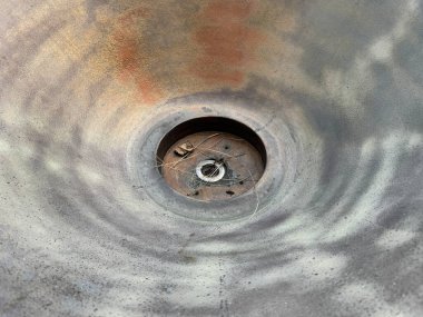 Yuvarlak, kırsal, yıpranmış ve ortasında yuvarlak bir delik olan bir metale yaklaş. Dekorasyon ya da diğer bina drenaj sistemi ya da kanalizasyon borusu için uygun.