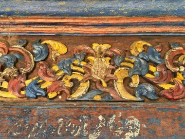Close up rustic classic wood panel carved with floral and swirls random pattern, in shades of vibrant blue, red, and yellow paint color. Rustic traditional carving, vintage feel. Seamless background texture.