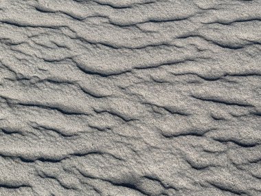 Rastgele dalgalanan buhar ve dalgalı desenle gri kum dokusunu kapat. Rüzgâr aşınması ve kum fırtınasının sonucu bu üç boyutlu hatları ve deseni oluşturur. Kusursuz arkaplan dokusu.