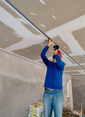 İnşaat işçisi, elektrikçi, bir çadırda lamba montajı yapıyor, demirbaşları çadıra vidalıyor..