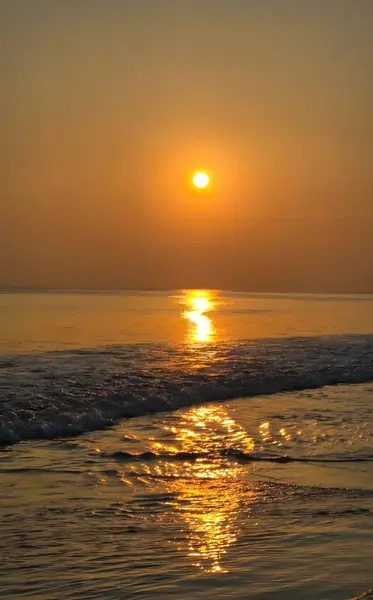 Güneş ışığının hafif dalgalar arasında yansımasıyla okyanus üzerinde şaşırtıcı altın gün batımı manzarası. Mükemmel doğa ve seyahat stoku.
