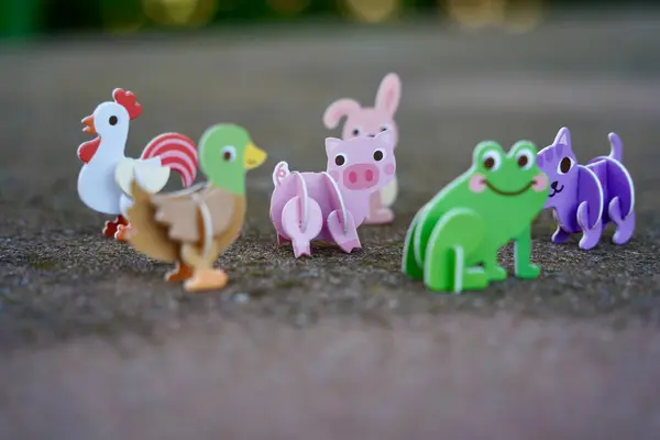 stock image Small cute colorful animal cardboard figures. Animal family figurines toys. Green Frog, red and white chicken and rooster, purple cat, pink pig, pink rabbit, brown and green duck. 2024.