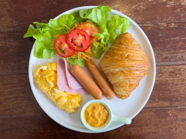 Ahşap bir yemek masasına doldurulmuş kruvasanlar. Tavuklu kruvasan, sosis, jambon, omlet, sebze, domates. Kahvaltı konsepti, fast food, aperatif. üst görünüm
