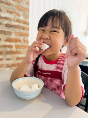 Kırmızı önlük giymiş, heyecanla lokumların tadını çıkaran bir çocuk. Tatlı ikram.