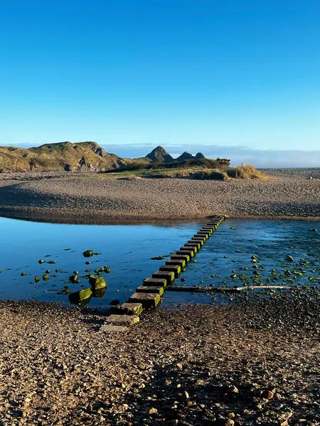 Galler, İngiltere 'de kumlu bir sahilde su üzerinde taş basmak.. 