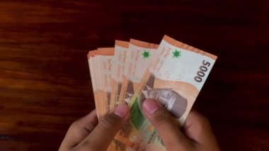 Beş bin rupia banknot tutan bir adam. Endonezya parası.