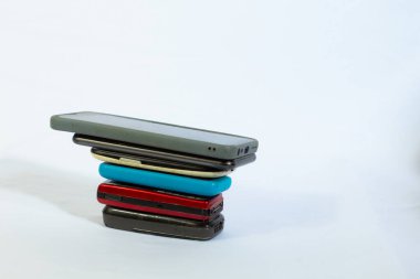Arka planda izole edilmiş yan açıyla çekilmiş bir yığın cep telefonu.