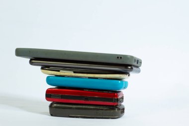 Arka planda izole edilmiş yan açıyla çekilmiş bir yığın cep telefonu.