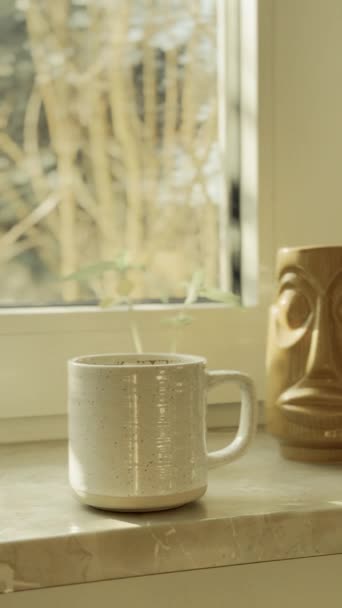 日光で窓に立っているホワイトカップのコーヒーと大気の居心地の良いビデオ — ストック動画