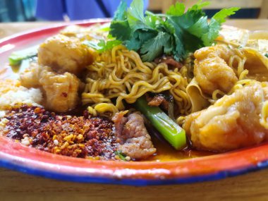 Lezzetli Asya yemeklerinin yakın görüntüsü. Yiyeceğe yakın. Bir tabak baharatlı sıcak çorba. Kızarmış hamur çubukları, hazır şehriyeler, baharatlı yağ, baharat üretimi.