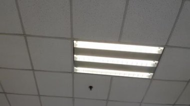 Modern ofiste duman sensörü, acil yangın söndürme fıskiyesi, havalandırma deliği ve çatıda otomatik perde kontrolörü olan iç ışık.