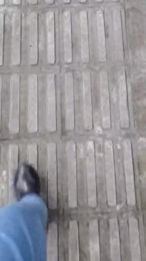 Mavi kot pantolonun altına siyah kısa botlar giyip yağmurlu bir günde dokunarak kaldırıma basan POV üst görüş bacağı. Yağmurlu bir günde yürüyüş konsepti. Ayaklarını ilk gören kişi. Yağmurlu bir günde yürür..