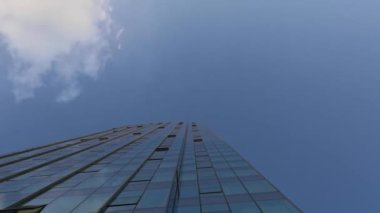 Soyut modern iş mimarisi. Camdan ve çelikten duvarlar, binaların ve mavi gökyüzünün yansımaları. Mavi gökyüzü altında uzun ve asil modern mimari ve beyaz bulutlar altında. Modern binanın düşük açılı görüntüsü..