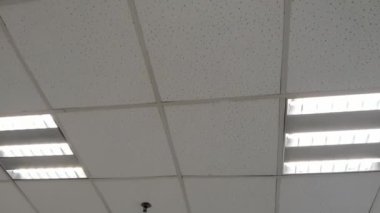 Modern ofiste duman sensörü, acil yangın söndürme fıskiyesi, havalandırma deliği ve çatıda otomatik perde kontrolörü olan iç ışık.