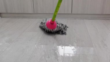 Hareket eden bir bez parçası gri ahşap zemini temizlemek için kullanılır. Kumaş paspas, ev hanımı ve hademenin bina zemininin kirini temizlemek veya cilalamak için kullandıkları bir ev işi aracıdır. 