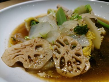 Baharatlı bir tabak nilüfer kökü, balmumu kabağı, patates ve yağ çorbası. Beyaz tabakta baharatlı sıcak kap, yiyecek konsepti.