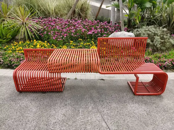 İnsanların oturup dinlenmesi için şık ve turuncu demir bir bank park edilir..