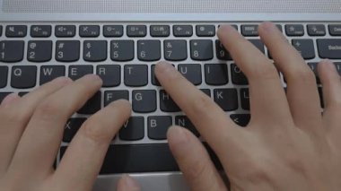 Evde dizüstü bilgisayarda klavyeyle yazı yazan bir kadının yakın çekim görüntüsü. Bir iş ortamında modern çalışma ve profesyonel aktivite. Dikey video.