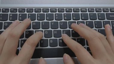 Evde dizüstü bilgisayarda klavyeyle yazı yazan bir kadının yakın çekim görüntüsü. Bir iş ortamında modern çalışma ve profesyonel aktivite. Dikey video.