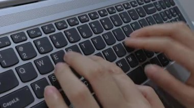 Evde dizüstü bilgisayarda klavyeyle yazı yazan bir kadının yakın çekim görüntüsü. Bir iş ortamında modern çalışma ve profesyonel aktivite. Dikey video.