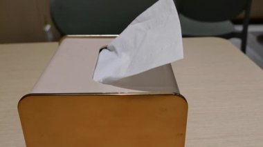 Kirli sarı plastik bir kutunun içindeki kağıt mendil restoranda misafir kullanımı için çıkarılıyor.