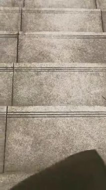 POV üst görüş bacağı siyah spor ayakkabılarla mavi kot pantolonun altında kırmızı çoraplarla ve yün paltoyla Merdivenlerden Aşağı Yürüme konsepti. İlk adım atma görüntüsü.