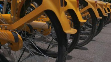 Paslı lekeli ve parlak güneş ışığının altında bisiklet kırmızı arka lambası. Yol kenarındaki Parlak Sarı Paylaşımlı Bisikletler Yol ve ofis binasının yanına park edilmiş.