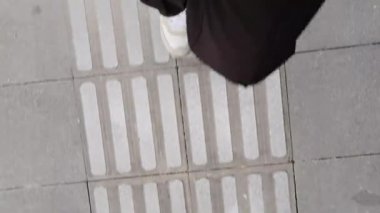 POV üst görüş bacağı siyah pantolonun altında, dokunsal kaldırıma basıyor. Yemeği sindirmek için yemekten sonra yürüyün..