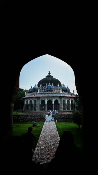 stock image New Delhi, India - August 7, 2024: Humayun's Tomb framed beautifully under an archway, highlighting symmetry and grand scale of Mughal architecture. Humayun's Tomb, Popular Tourist Attraction in Delhi