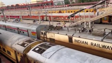 Varanasi, Uttar Pradesh, Hindistan - 24 Eylül 2024: Renkli kumaş çantalar bir trenin kapısında oturmuş kalkışı beklerken Varanasi tren istasyonunda mobil bir oyun oynayan adam.