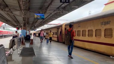 Varanasi, Uttar Pradesh, Hindistan - 24 Eylül 2024: Yolcular güzel bir sabahta Varanasi Cantt Tren İstasyonu 'ndaki trenlerine doğru bavullarıyla yürür, seyahat ve geçiş sergilerler.
