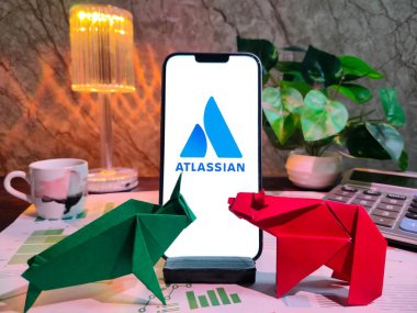 NewYork, USA- 15 Aralık 2024: ATLASSIAN borsa analizi üzerine seçici odaklanma grafikler, grafikler, hesap makinesi ve kahvenin yer aldığı ATLASSIAN Inc logosu ile finansal içgörüler için akıllı bir telefon