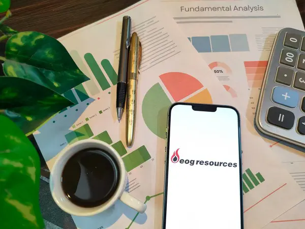 NewYork, ABD - 15 Aralık 2024: EOG RESOURCES borsa analizi üzerine seçici odaklanma grafikler, grafikler, hesap makinesi ve kahvenin yer aldığı EOG RESOURCES logosu ile finansal içgörüler için akıllı bir telefonda