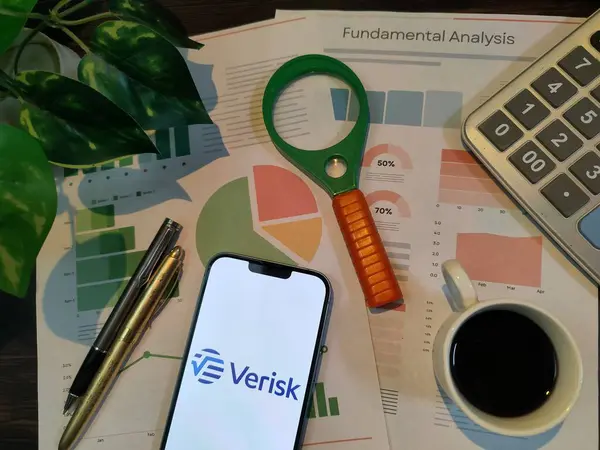 New York, ABD - 15 Aralık 2024: Veritabanı borsa analizi üzerine seçici odaklanma grafikler, grafikler, hesap makinesi ve kahve, mali içgörüler için VERISK logosu üzerinde akıllı telefon