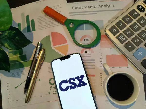 New York, ABD - 15 Aralık 2024: CSX borsa analizi üzerine seçici odaklanma grafikler, grafikler, hesap makinesi ve kahve, finansal içgörü için bir akıllı telefon üzerinde CSX logosu