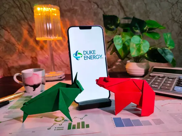 New York, ABD - 15 Aralık 2024: DUKE ENERGY Borsa Analizi üzerine Seçici Odaklanma Haritalar, grafikler, hesap makinesi ve kahvenin yer aldığı borsa analizi, DUKE ENERGY Inc logosu ile finansal içgörüler için akıllı telefon