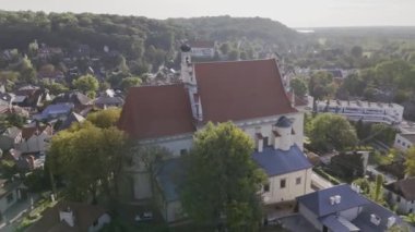 Polonya 'nın Kazimierz Dolny kentindeki güzel tarihi kilise ve ortaçağ şatosunu Vistula Nehri manzaralı bir manzarayla yakalayan insansız hava aracı. Seyahat, tarih ve mimariyle ilgili içerik için mükemmel.