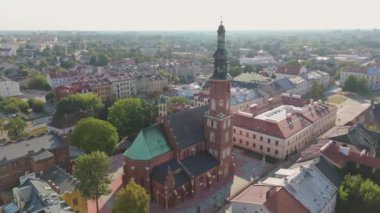 İnsansız hava aracı, büyüleyici bir kasabada çatıları ve yeşillikleri olan tarihi bir kilise kulesini gösteriyor. Mimarlık, seyahat ve tarihsel içerik için mükemmel, kentsel manzaraları ve mirası vurgulamak.
