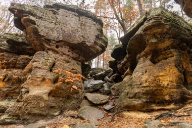 Doğanın büyüleyici güzelliğini keşfedin. Bu büyüleyici antik kaya oluşumları görüntüsü yemyeşil bir ormanın derinliklerine yerleşmiştir. Yükselen kayalar ve çevreleyen ağaçlar gizemli ve büyülü bir atmosfer yaratıyor..