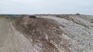 Yoğun ormanlar ve tarımsal alanlarla çevrili kırsal bir alanda yer alan büyük bir çöp sahasının hava perspektifi. Çelişkili manzara, atık yönetiminde çevre sorunları vurguluyor