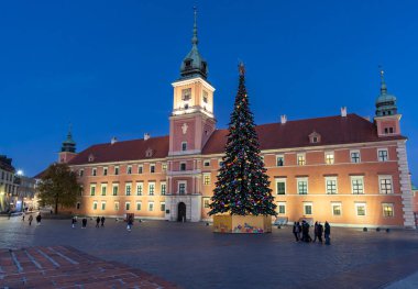 A beautiful Christmas market is set up in front of a historic royal castle. A large, decorated Christmas tree stands in the center, surrounded by people enjoying the festive atmosphere.Poland Warsaw 01.12.2024 clipart