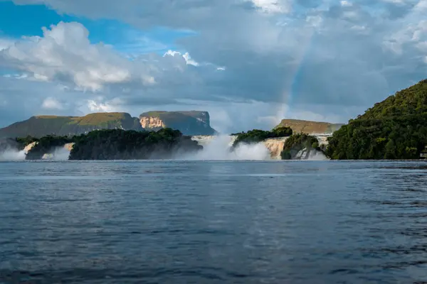 Canaima Gölü 'nün üzerinde gökkuşağı. Arka planda Canaima Ulusal Parkı Tepuis' leri, Venezuela.
