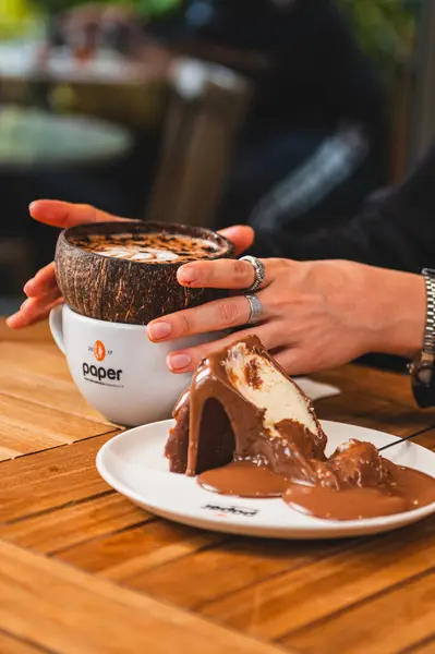 Bir kafede elinde pasta tutan bir kişinin dikey görüntüsü.