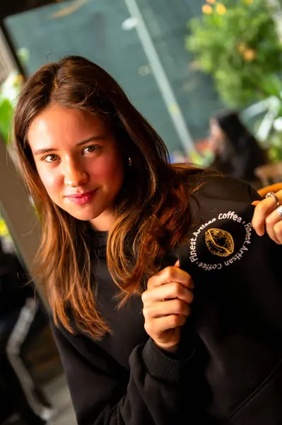 Kafede elinde kahve tutan genç bir kadın.