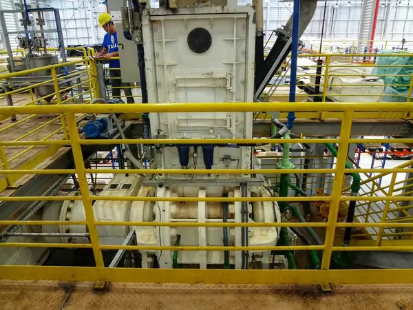 Görüntü, merkezinde bir çeşit motor ya da pompa gibi görünen büyük bir makine parçasıyla endüstriyel bir ayar gösteriyor. Ona bağlı çeşitli boru ve vanalar var..