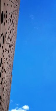 Bu fotoğraf mavi gökyüzü ile çelişen, fütüristik bir fikir veren delikleri olan bir yapıyı gösteriyor..