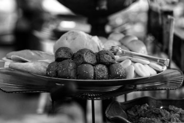 Siyah ve beyaz resim, yuvarlak bir sepette sıralanmış taze pişmiş ekmekleri gösteriyor..