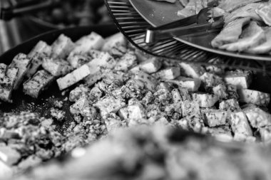 Siyah ve beyaz resim, bir tabak Gorgonzola peynirinin, bitki ve baharatlarla süslenmiş yakın çekimini gösteriyor..