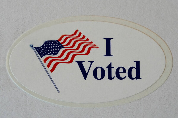 "I Voted "Наклейка с американским флагом на бумаге.  